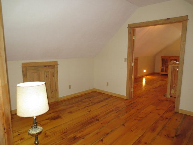 bonus room with hardwood / wood-style floors and vaulted ceiling