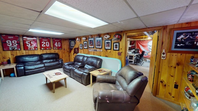 living room featuring carpet floors, a paneled ceiling, and wood walls