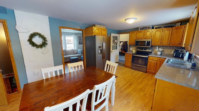 kitchen featuring light wood-type flooring, stainless steel appliances, tasteful backsplash, and sink