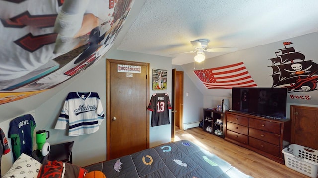 bedroom with ceiling fan, a textured ceiling, a baseboard heating unit, and light hardwood / wood-style flooring