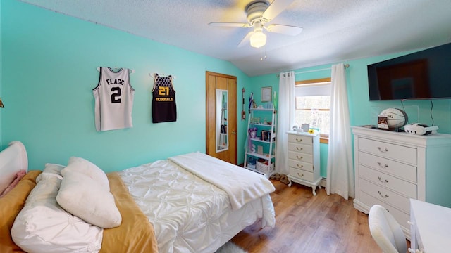 bedroom featuring ceiling fan, a textured ceiling, lofted ceiling, and light wood-type flooring