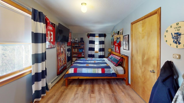 bedroom featuring light wood-type flooring and a baseboard radiator