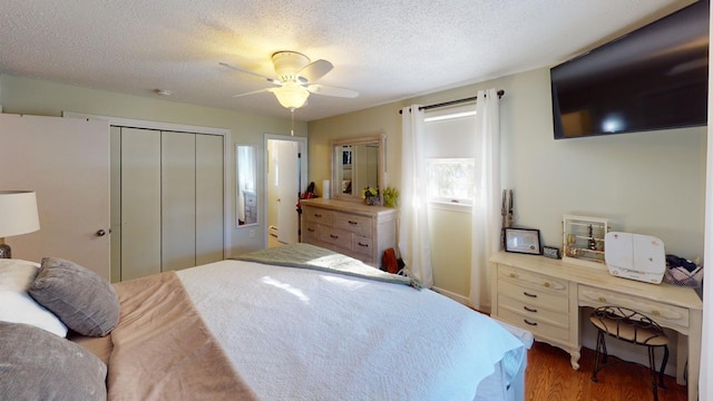 bedroom with a textured ceiling, ceiling fan, a closet, and wood-type flooring