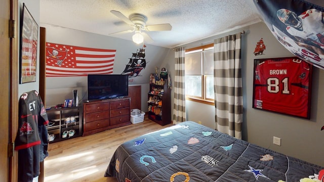 bedroom with ceiling fan, wood-type flooring, and a textured ceiling