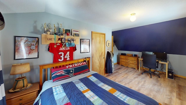 bedroom featuring light wood-type flooring, a textured ceiling, and lofted ceiling