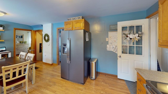 kitchen featuring stainless steel refrigerator with ice dispenser, light hardwood / wood-style floors, and range