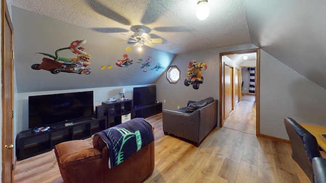 living room with ceiling fan, a textured ceiling, light hardwood / wood-style flooring, and vaulted ceiling