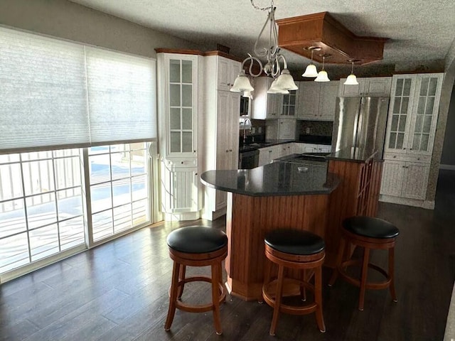 kitchen featuring pendant lighting, white cabinets, a kitchen island, dark hardwood / wood-style flooring, and a breakfast bar area