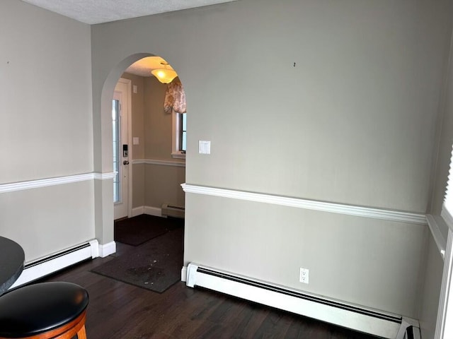 spare room featuring dark wood-type flooring and a baseboard heating unit