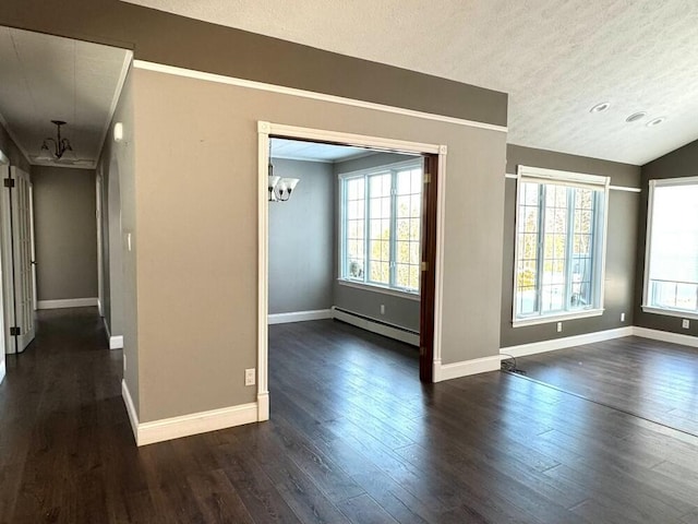 spare room featuring dark wood-type flooring, a baseboard radiator, a healthy amount of sunlight, and an inviting chandelier