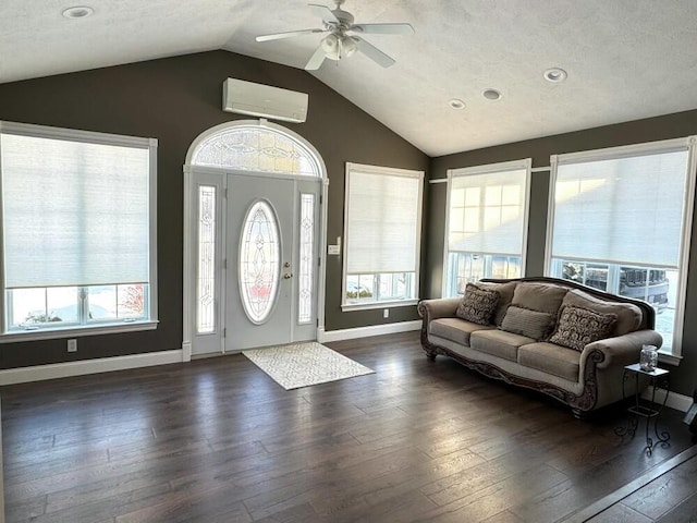 foyer entrance featuring an AC wall unit, dark wood-type flooring, a textured ceiling, and lofted ceiling