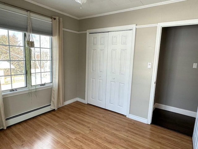 unfurnished bedroom with baseboard heating, multiple windows, light hardwood / wood-style flooring, and a closet