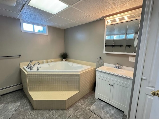 bathroom featuring tiled tub, a baseboard radiator, tile patterned floors, vanity, and a paneled ceiling