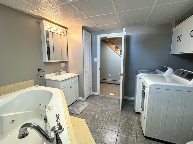 bathroom with a baseboard radiator, tile patterned flooring, a paneled ceiling, a bathing tub, and washer and clothes dryer