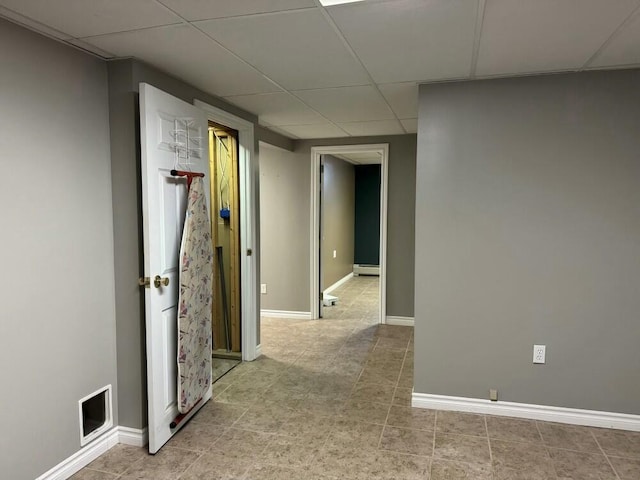 hall with a baseboard radiator and a paneled ceiling