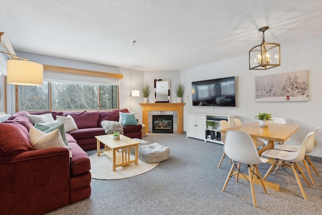 living room featuring a fireplace, carpet, a textured ceiling, and a notable chandelier