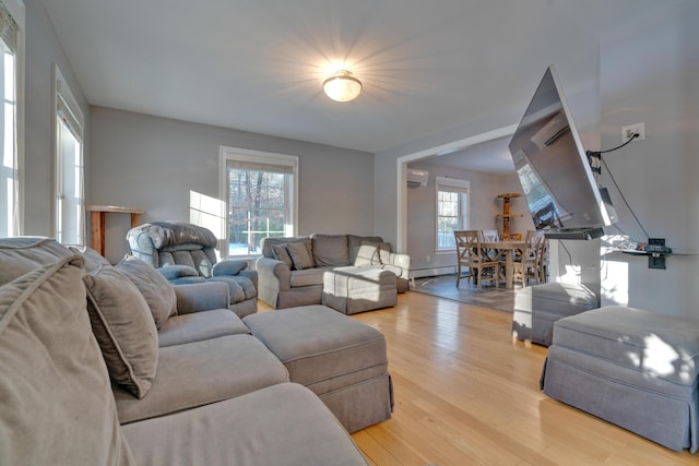 living room featuring a baseboard heating unit, a wall unit AC, light hardwood / wood-style floors, and plenty of natural light