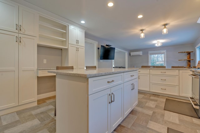 kitchen with white cabinets, a center island, light stone counters, an AC wall unit, and a kitchen bar