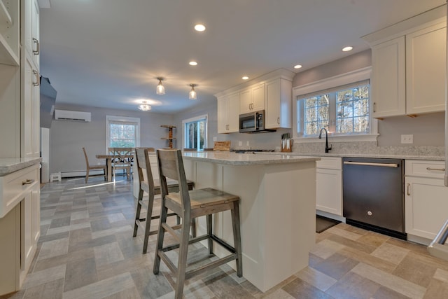 kitchen featuring white cabinetry, light stone countertops, a kitchen island, a wall mounted air conditioner, and appliances with stainless steel finishes