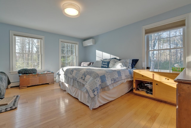 bedroom with a wall mounted AC, light wood-type flooring, multiple windows, and baseboard heating