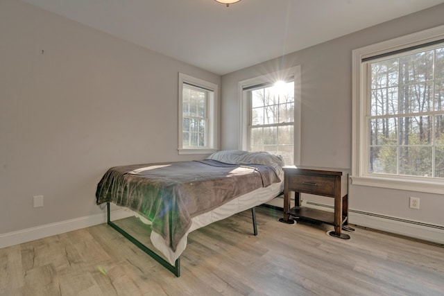 bedroom with a baseboard radiator and hardwood / wood-style flooring