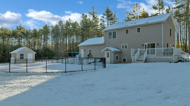 snow covered property with a swimming pool side deck and an outdoor structure