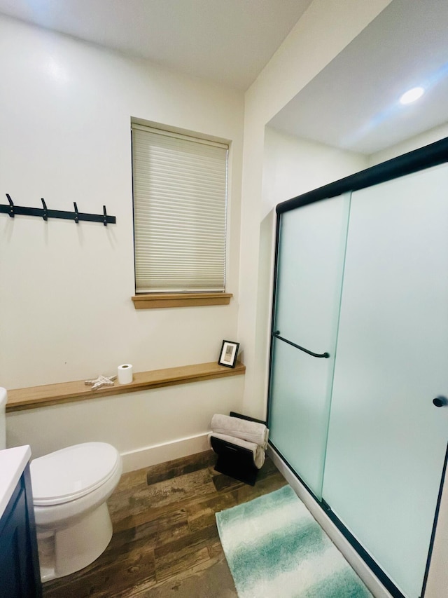 bathroom with vanity, toilet, a shower with shower door, and wood-type flooring