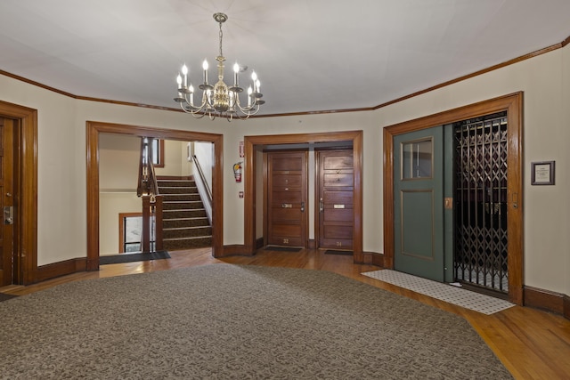 entryway featuring dark hardwood / wood-style flooring, ornamental molding, and an inviting chandelier