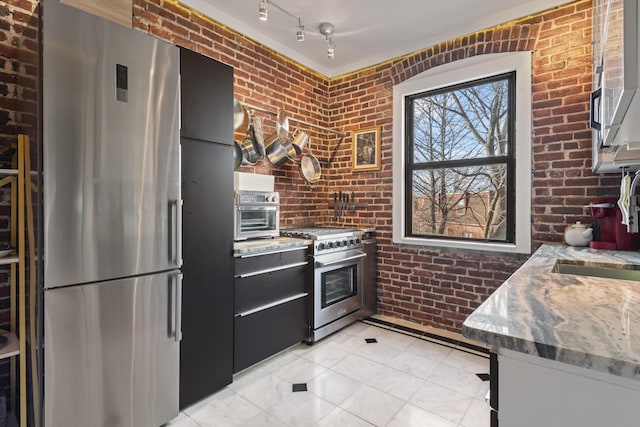 kitchen featuring sink, stainless steel appliances, light stone counters, brick wall, and light tile patterned flooring