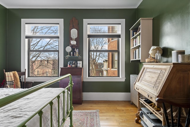 bedroom featuring radiator, crown molding, and light hardwood / wood-style flooring