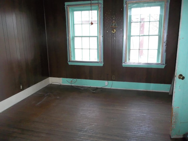 empty room featuring plenty of natural light and dark hardwood / wood-style floors