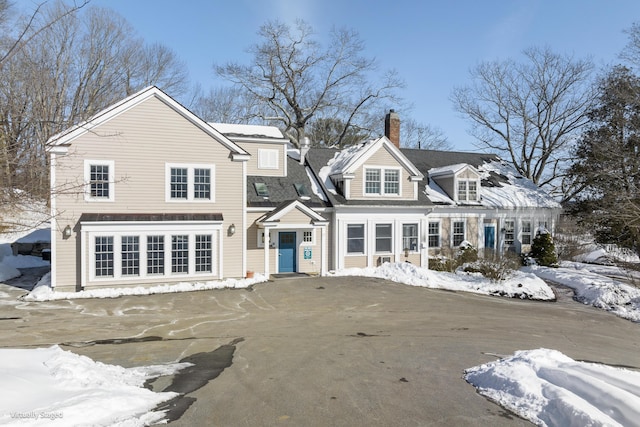 snow covered rear of property featuring a chimney