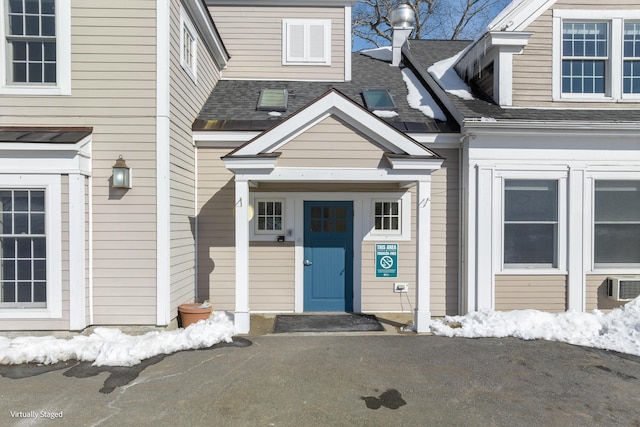 doorway to property featuring roof with shingles