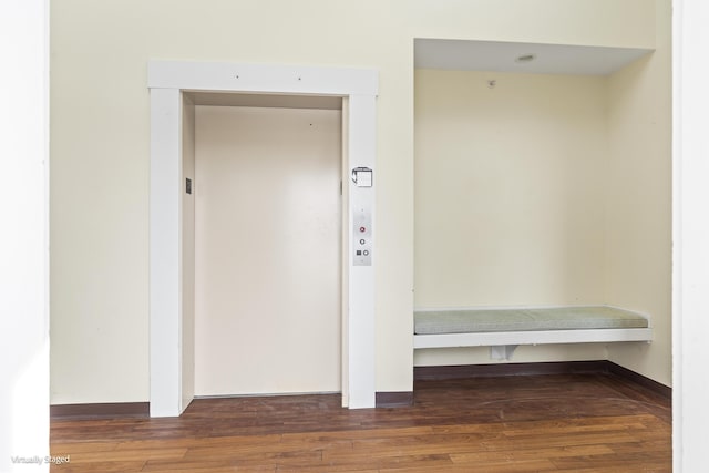 interior space with dark wood-type flooring, elevator, and baseboards