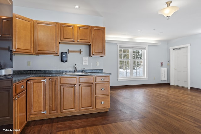 kitchen with dark countertops, dark wood finished floors, brown cabinets, and a sink