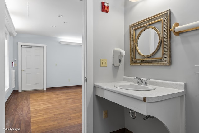 bathroom featuring wood finished floors, a sink, and baseboards