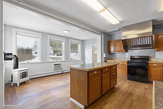 kitchen featuring brown cabinetry, black range with electric stovetop, a center island, light wood-type flooring, and a baseboard heating unit