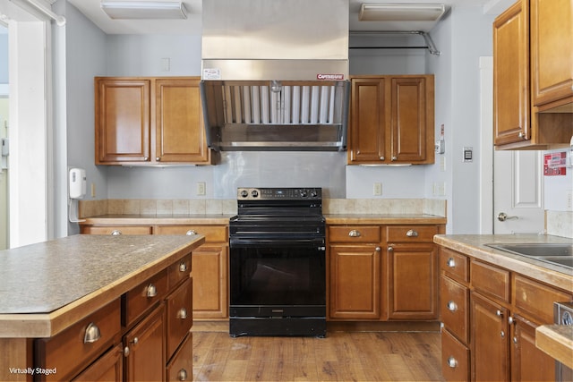 kitchen with brown cabinets, a center island, light wood-type flooring, and black range with electric cooktop