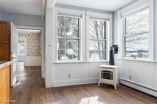 interior space featuring a healthy amount of sunlight, a wood stove, and baseboard heating