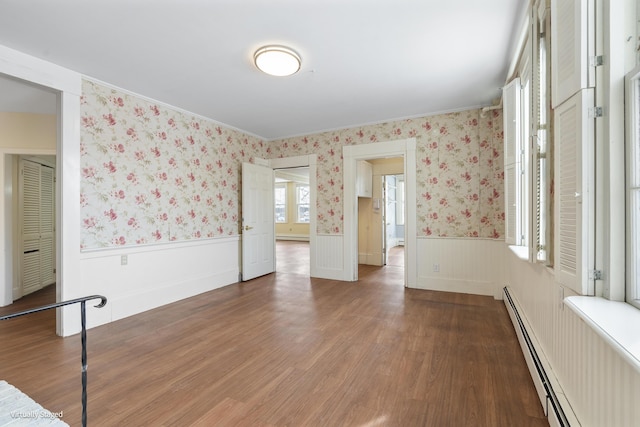 empty room with a baseboard radiator, a wainscoted wall, dark wood-style flooring, baseboard heating, and wallpapered walls