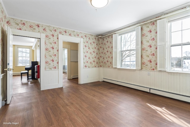 spare room with a baseboard heating unit, wainscoting, dark wood finished floors, and wallpapered walls