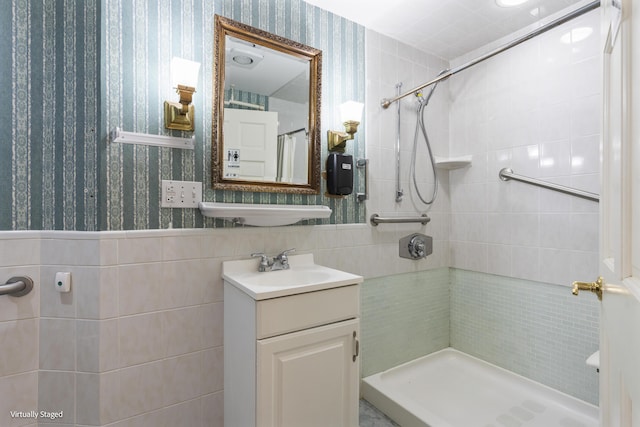 bathroom with a stall shower, wainscoting, tile walls, and wallpapered walls