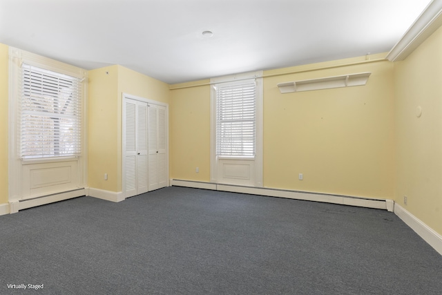 unfurnished bedroom with baseboards, baseboard heating, a closet, and dark colored carpet