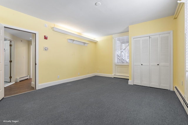 unfurnished bedroom featuring a baseboard heating unit and dark colored carpet