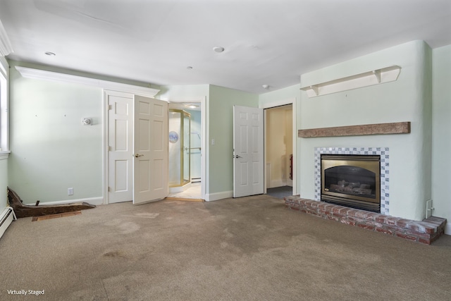 unfurnished living room with carpet flooring, a glass covered fireplace, and baseboards