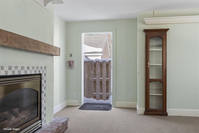 living area with a brick fireplace, baseboards, and light colored carpet