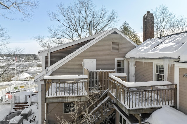 snow covered house with a wooden deck