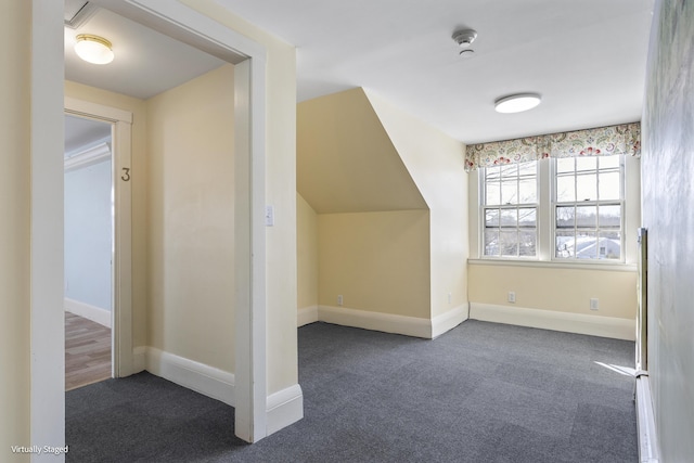 additional living space featuring baseboards and dark colored carpet