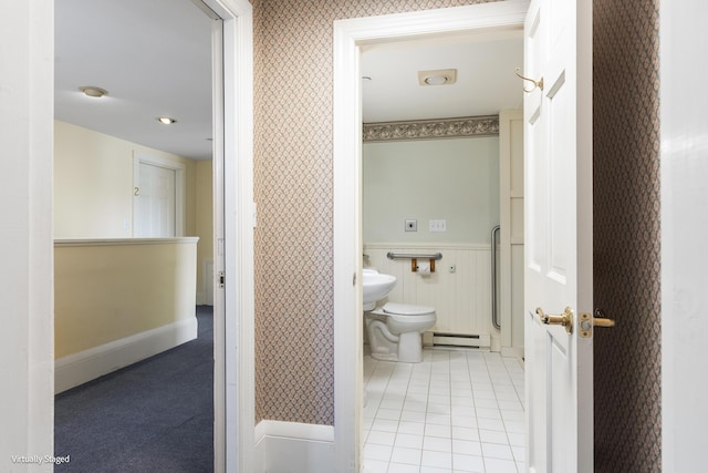 bathroom with toilet, baseboard heating, wainscoting, tile patterned floors, and wallpapered walls