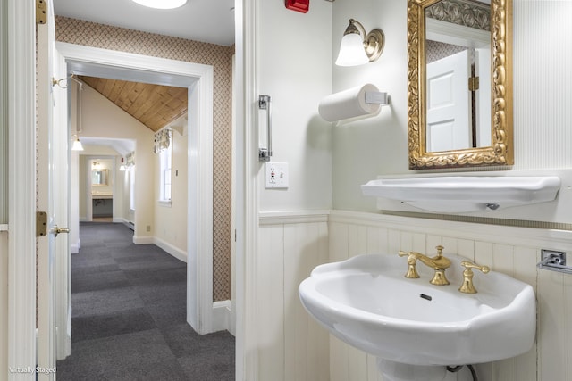 bathroom featuring lofted ceiling, wainscoting, and a sink